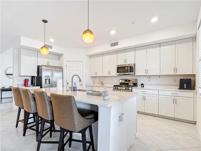 Kitchen featuring white cabinets, hanging light fixtures, sink, and appliances with stainless steel finishes