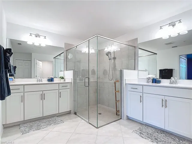 Bathroom featuring tile patterned floors, vanity, and an enclosed shower