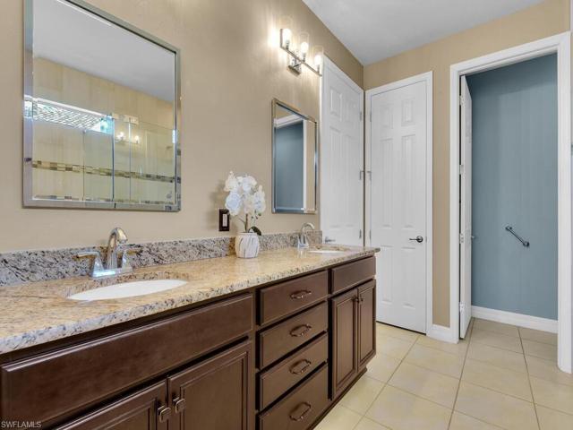 Primary bathroom with rich wood cabinetry and granite countertops with dual sinks