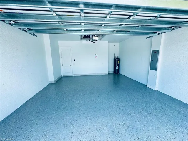 Garage featuring a garage door opener, electric panel, and electric water heater