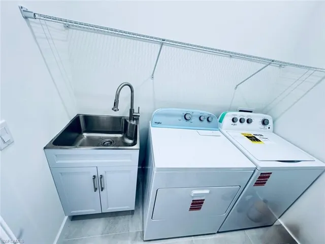 Laundry room with separate washer and dryer, a sink, and cabinet space