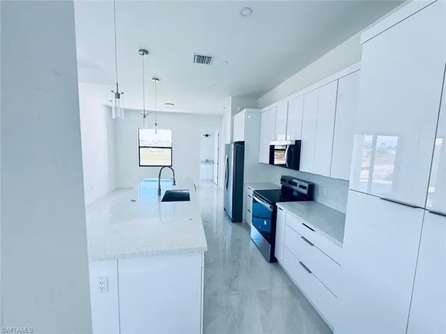 Kitchen featuring visible vents, white cabinets, modern cabinets, appliances with stainless steel finishes, and a sink