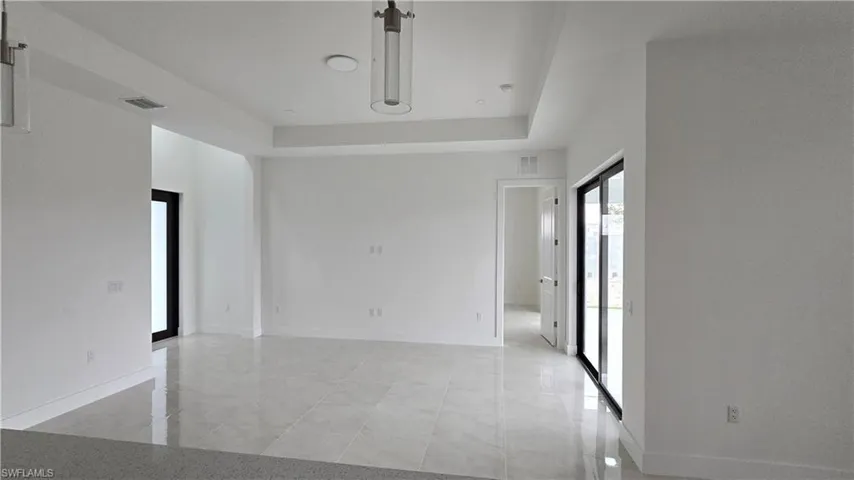 Spare room featuring a tray ceiling, visible vents, and baseboards