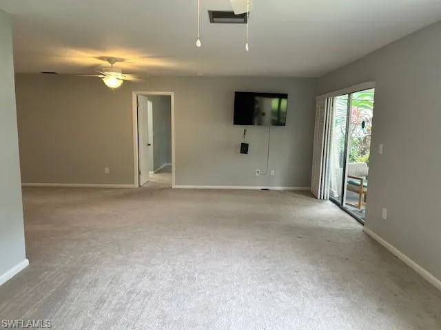 Unfurnished living room featuring carpet and a ceiling fan