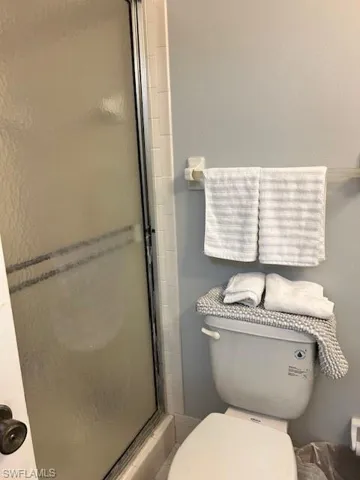 Full bath featuring a shower stall and toilet