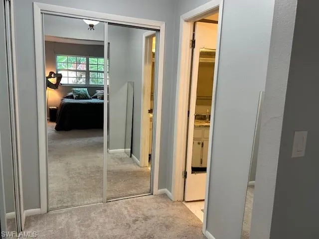 Hallway featuring light colored carpet and baseboards