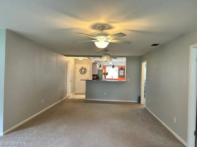 Unfurnished Dining and living room featuring light gray colored carpet and a ceiling fan