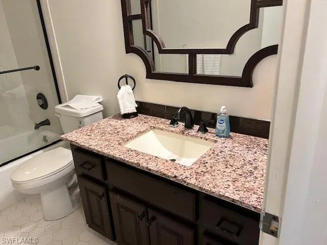 Full bath featuring vanity, enclosed tub / shower combo, and light tile patterned floors