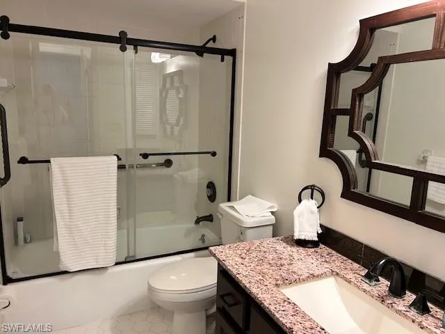Bathroom featuring bath / shower combo with glass door, vanity, and tile patterned flooring