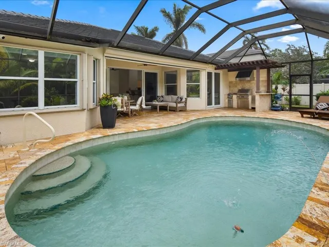 View of swimming pool featuring a patio area, glass enclosure, exterior kitchen, ceiling fan, and outdoor lounge area