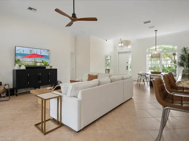 Living room with crown molding, light tile patterned flooring, and ceiling fan