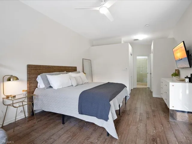 Bedroom featuring ensuite bath, dark wood-type flooring, and ceiling fan