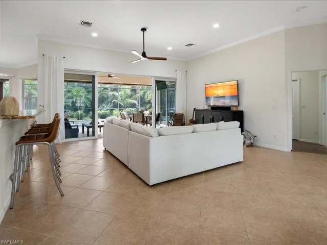 Tiled living room featuring ceiling fan and ornamental molding
