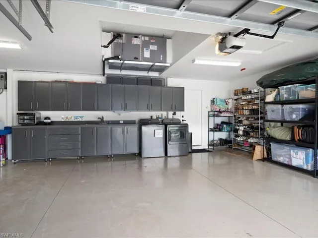 Garage featuring sink, a garage door opener, and independent washer and dryer