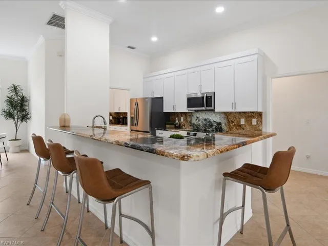 Kitchen with a kitchen breakfast bar, kitchen peninsula, white cabinetry, and stainless steel appliances
