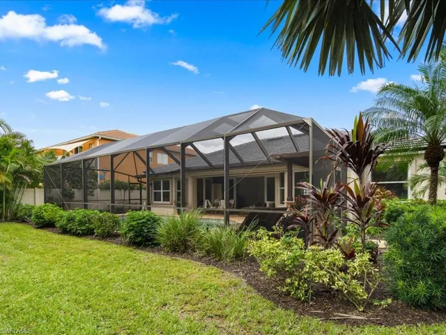 Rear view of house featuring a yard and glass enclosure