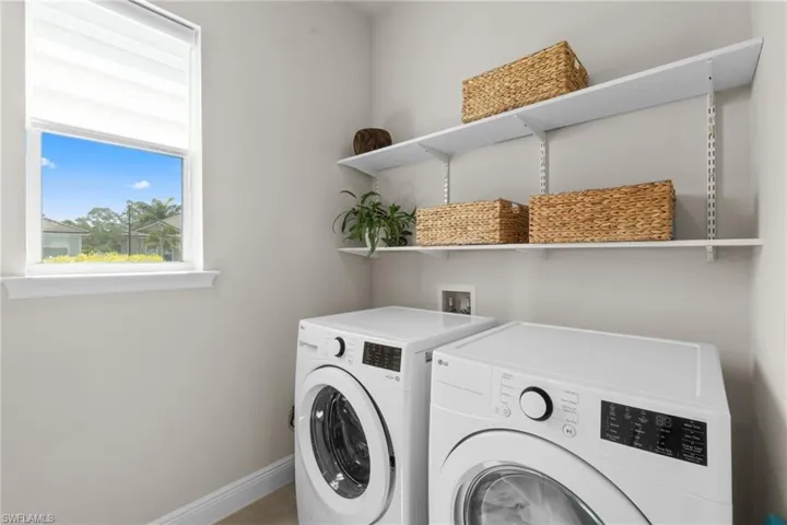 Well Appointed Laundry Room with shelveing, as well as a utility sink and custom cabinets, on the opposite wall.
