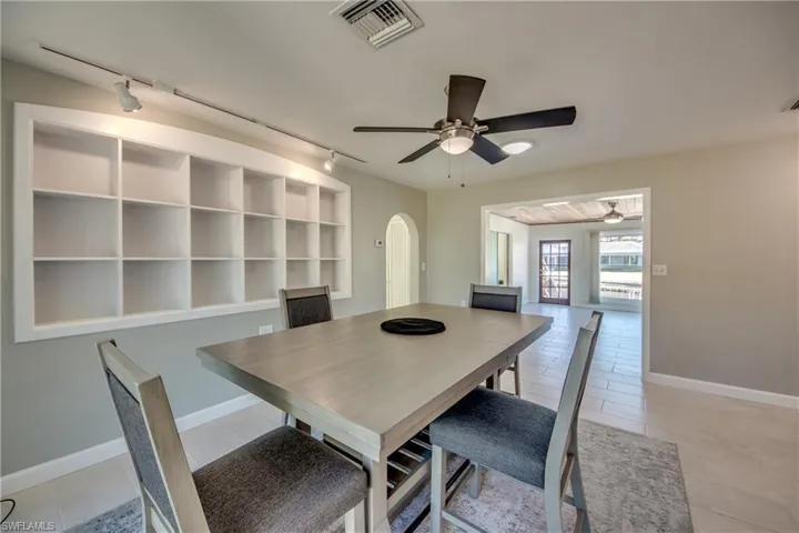Tiled dining space featuring ceiling fan and rail lighting