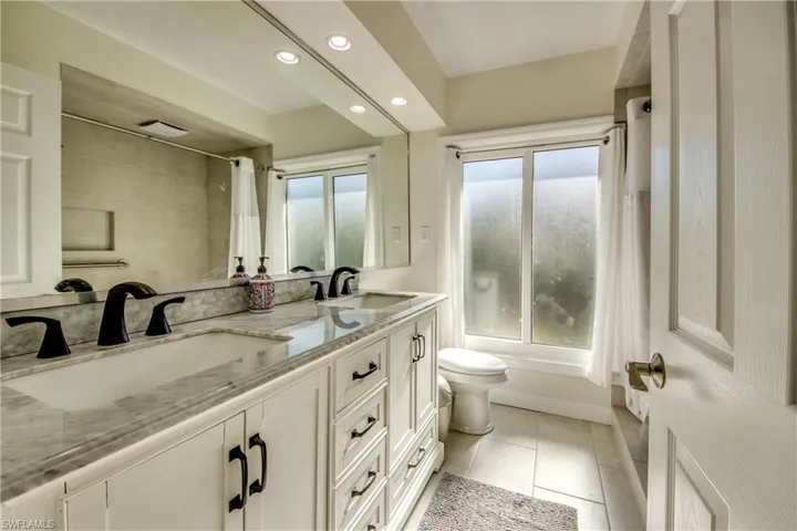 Full bathroom with shower / bath combination with curtain, vanity, toilet, and tile patterned floors
