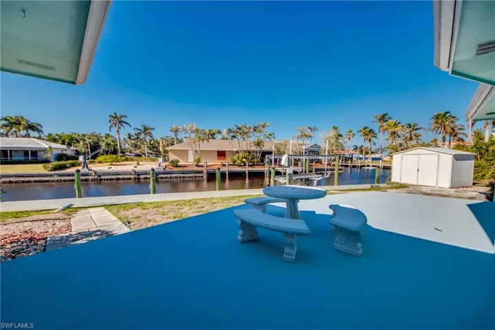 View of swimming pool featuring a boat dock, a water view, and a storage shed