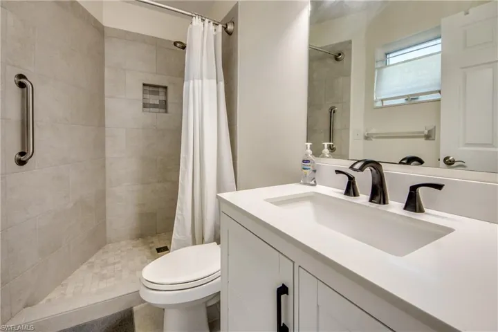 Bathroom featuring a shower with curtain, vanity, and toilet