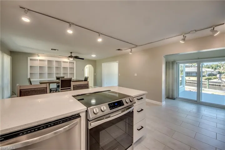 Kitchen with ceiling fan, white cabinetry, stainless steel appliances, and light tile patterned floors