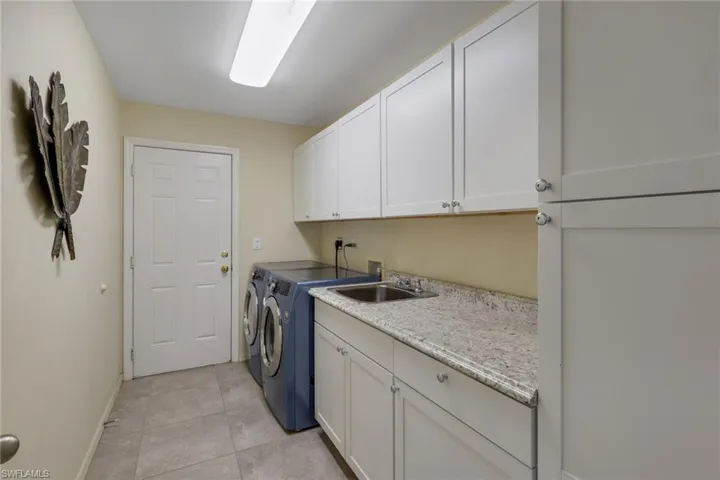 Laundry area with cabinet space, washing machine and dryer, and light tile patterned floors