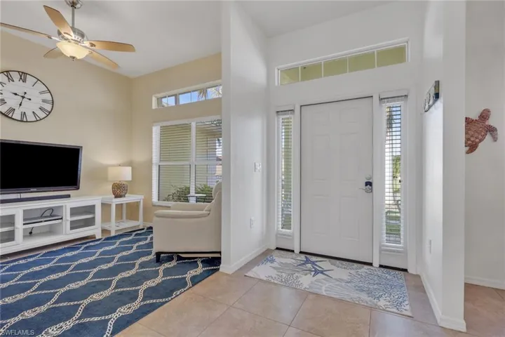 Entrance foyer featuring light tile patterned floors, ceiling fan, and a high ceiling