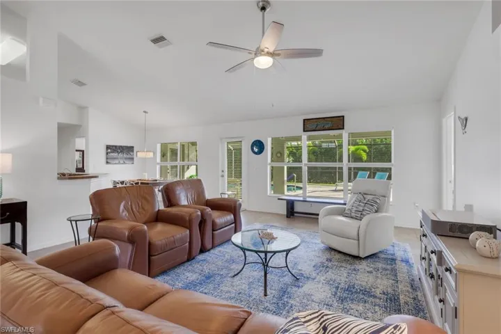 Living room featuring lofted ceiling, ceiling fan, and healthy amount of natural light