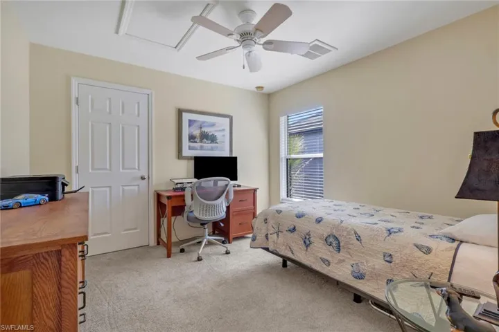 Bedroom with an office area, light carpet, and ceiling fan