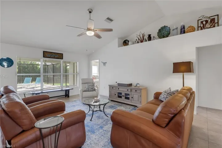 Tiled living area featuring vaulted ceiling and a ceiling fan