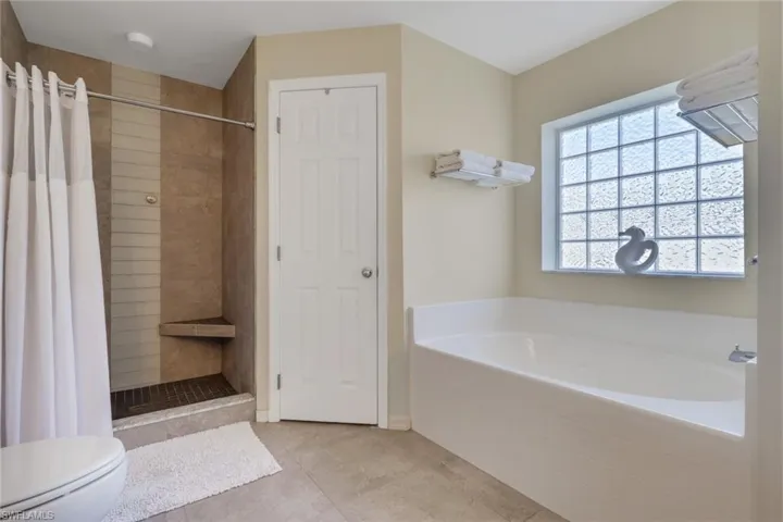 Full bathroom featuring a stall shower, a garden tub, and tile patterned flooring