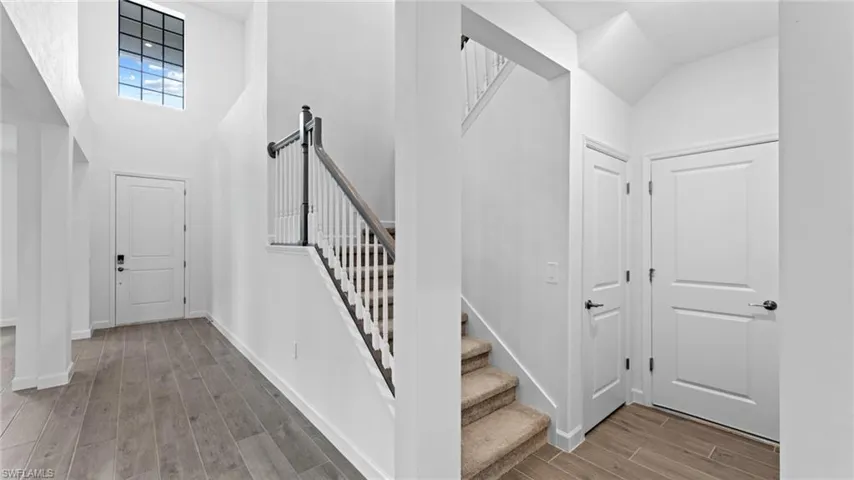 Foyer featuring high vaulted ceiling and wood-type flooring