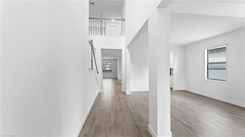 Corridor with light hardwood / wood-style floors and a towering ceiling