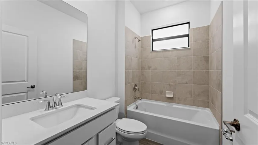 Full bathroom with vanity, tiled shower / bath combo, and toilet