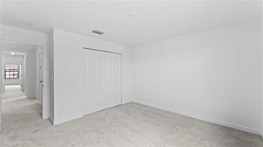 Unfurnished bedroom featuring a closet and light colored carpet