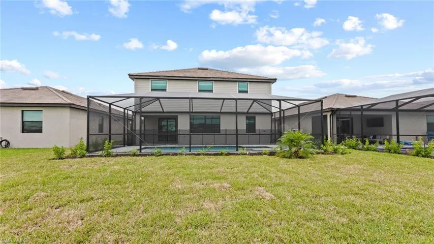 Rear view of house with a lawn and a lanai