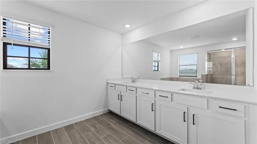 Bathroom featuring an enclosed shower, wood-type flooring, plenty of natural light, and dual bowl vanity