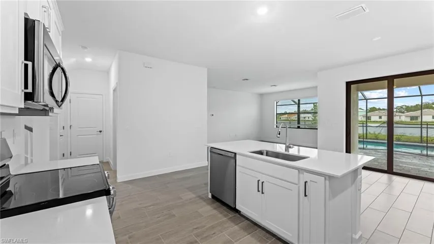 Kitchen featuring stainless steel appliances, white cabinets, sink, light hardwood / wood-style flooring, and a kitchen island with sink