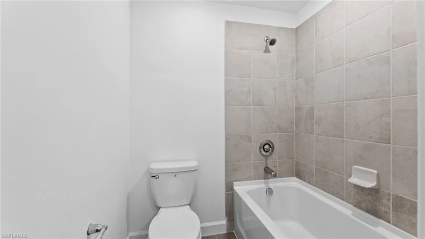 Bathroom with tiled shower / bath combo and toilet