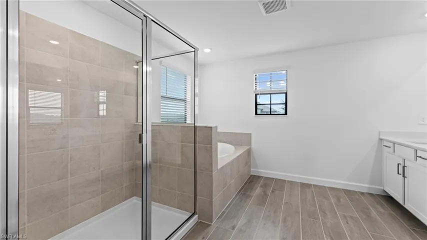 Bathroom featuring hardwood / wood-style flooring, independent shower and bath, and vanity