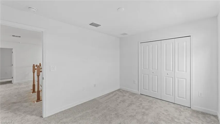 Unfurnished bedroom featuring light carpet and a closet