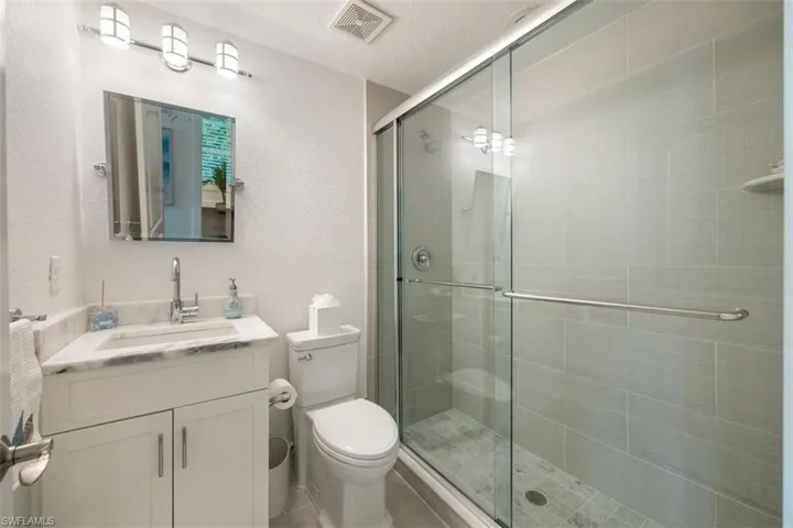 Bathroom featuring vanity, a shower stall, and a textured wall
