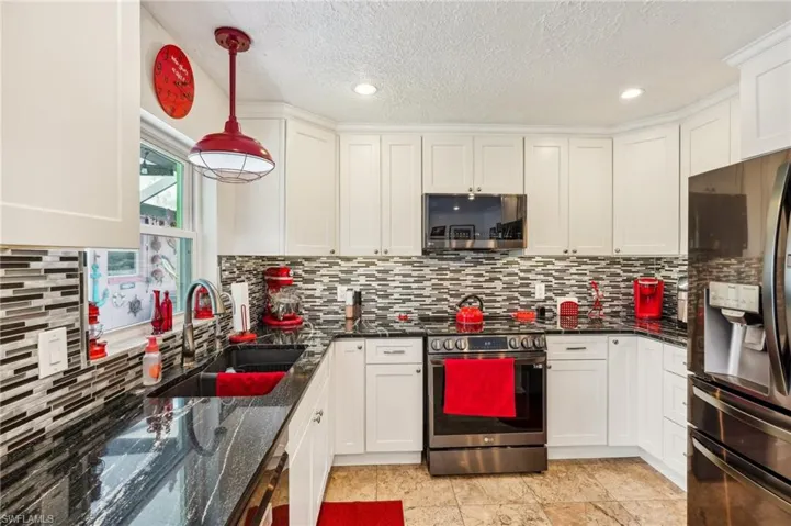 Kitchen featuring appliances with stainless steel finishes, decorative backsplash,  granite countertops and white cabinets
