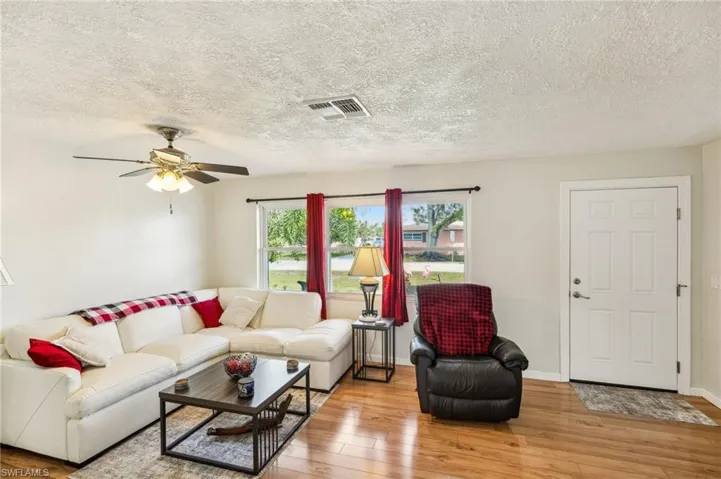 Living area with light wood laminate flooring and a ceiling fan