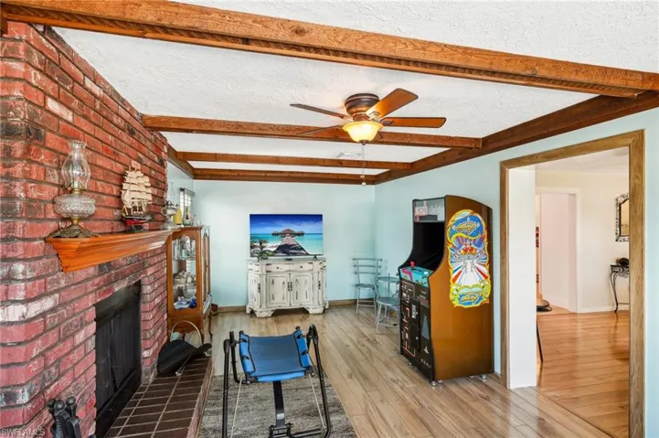 Family room with a fireplace and wood beamed ceiling with light wood laminate flooring