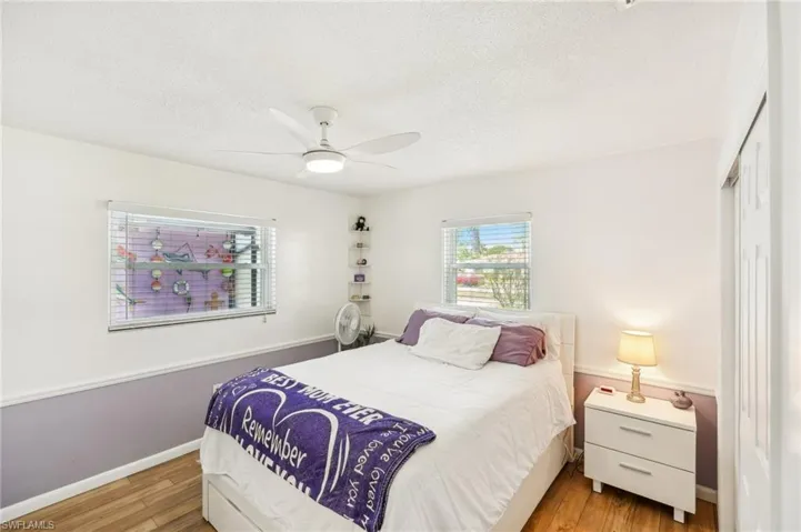 Bedroom with an ensuiite bathroom, ceiling fan and light wood laminate flooring