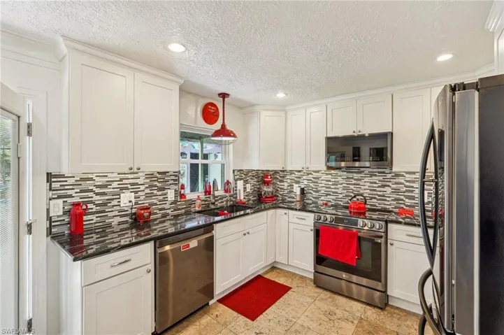 Kitchen featuring appliances with stainless steel finishes, decorative backsplash,  granite countertops and white cabinets