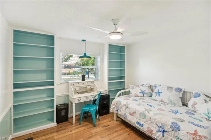 Bedroom 2 featuring, built in shelving, light wood lamited floors with a ceiling fan