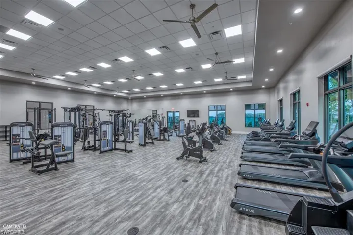 Gym featuring a high ceiling, ceiling fan, and a drop ceiling